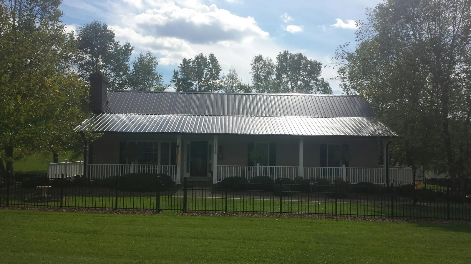 Gray metal roof on a brick ranch with a full width front porch — Gutter Guard Installation work by our crew in Hillsborough