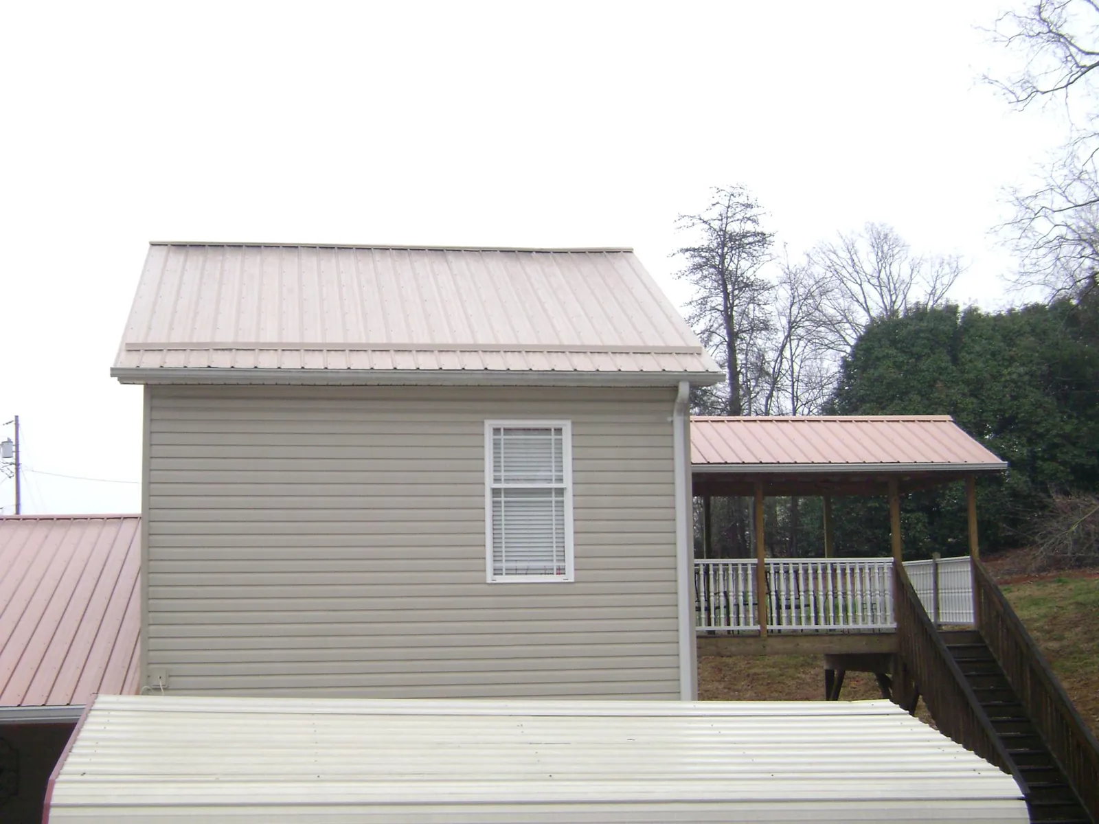 Tan metal roofs on a two story addition and attached porch, from a Roof Replacement job in Hillsborough